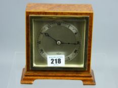 An Elliott burr walnut encased mantel clock having a silvered dial with Roman numerals set behind