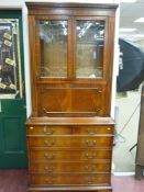 A reproduction mahogany cabinet on chest having a moulded cornice over two cut glass doors with