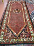 A red ground runner with pattern similar to paisley design, approximately 295 x 150 cms