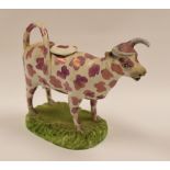 SWANSEA POTTERY - lustre sponge decorated cow-creamer on grassy base, 18cms long