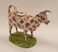 SWANSEA POTTERY - lustre sponge decorated cow-creamer on grassy base, 18cms long