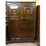 An oak Jacobean style two door wardrobe with raise chamfered door panels and additional applied