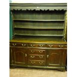 An 18th Century North Wales oak dresser, the three shelf wide boarded rack with shaped front