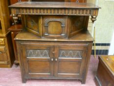 A good quality reproduction oak court cupboard having a deep carved frieze, carved arch inset