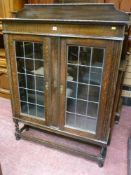 An oak two door railback bookcase with leaded glass doors on barley twist supports, 145 cms