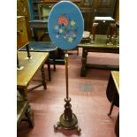 A Victorian mahogany polescreen with embroidered oval face panel, turned column base with carved