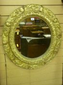 A 19th Century circular pine mirror with gilt decorated gesso floral relief, 67 cms diameter (gilt