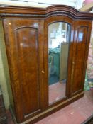 A good Victorian mahogany triple door wardrobe with arched crown and central mirrored door on a