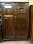 An oak Jacobean style two door wardrobe with raise chamfered door panels and additional applied