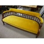 An Edwardian carved mahogany salon settee, the curved spindle gallery back with padded upholstered