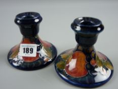 A Moorcroft Pomegranate blue ground pair of short candlesticks, impressed factory marks to the