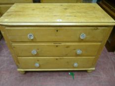 A Victorian stripped pine chest of three drawers with glass knobs on turned bun feet, 80 x 96 cms