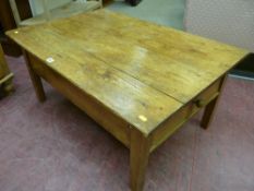 An antique and later stripped pine coffee table with single end storage drawer on block supports, 46