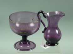 An early amethyst glass cream jug and sugar bowl with traces of gilt decoration, including the words