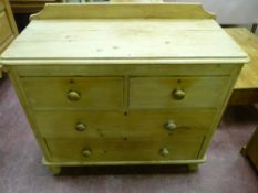 A Victorian stripped pine railback chest of two short over two long drawers with turned wooden knobs