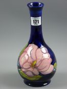 A Moorcroft Magnolia bottle shaped narrow necked vase, tube line decorated on a cobalt blue