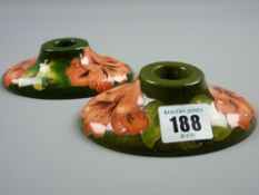 A Moorcroft Coral Hibiscus green ground pair of squat form candleholders, 12.5 cms long