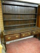 A George II and later Shropshire oak dresser, the tall closed back three shelf rack on a plank top