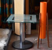 A modern glass topped table with chrome supports and marble base together with a retro space age