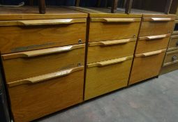 A trio of wooden filing drawers
