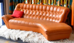 A tan leather effect curve shaped settee circa 1970