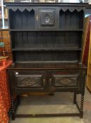 A stained oak country dresser with semi-open rack above and on bobbin supports and with carved door