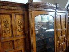 A late nineteenth century marquetry satinwood triple wardrobe of architectural form and having a