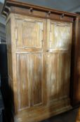 A limed oak two drawer armoire of panelled form and with raised cornice, 122cms wide x 210cms high
