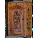 A pine hanging corner cupboard with single arched door and profusely painted in the barge ware style