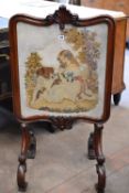 A late Victorian mahogany firescreen with a needlework scene of child and dogs in an elaborate frame