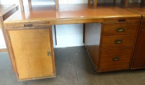 A vintage kneehole office desk with cupboard flank and flank of three drawers
