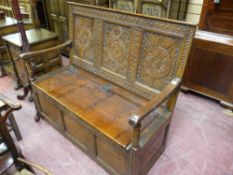 A good carved oak box seat settle with carved three panel back and iron hinges to the seat lid,