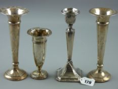 Three hallmarked silver trumpet bud vases and a single candlestick, various hallmarks, all loaded