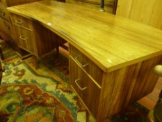 A stylish mid Century teak desk of four drawers under a curved top on turned tapering legs, 75 x 160