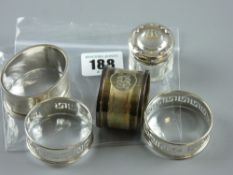 A small glass rouge pot with hallmarked silver lid and four hallmarked silver napkin rings (