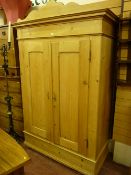 A 19th Century European stripped pine two door wardrobe with shaped pediment, 212 x 133 cms