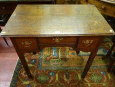 An early 19th Century oak lowboy having a narrow centre drawer with shaped apron and a box drawer