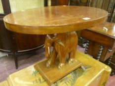 A hardwood oval topped table with carved elephant support on a rectangular base, 48 cms high