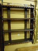 An Edwardian mahogany four shelf wall rack, each shelf with a shaped apron and with carved floral