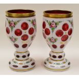 A PAIR OF BOHEMIAN OVERLAID CRANBERRY GLASS GOBLETS decorated with flowers and gilding, 17cms