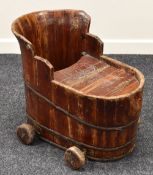 AN ANTIQUE CHILD'S BATH CHAIR of plank and iron bound construction with wooden wheels, 66 x 52 cms