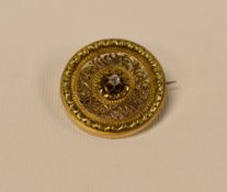 A CIRCULAR GOLD BROOCH WITH DIAMOND SOLITAIRE to the centre surrounded by a raised and filigree
