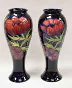 A PAIR OF MOORCROFT VASES tube-line decorated with red flowers on green stems on a blue reserve,