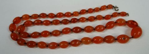 A NECKLACE STRAND OF FIFTY GRADUATED RED AMBER BEADS, 41cms long