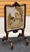 A MAHOGANY FIRESCREEN with acanthus leaf carved centre to the top and with an embroidered scene of a