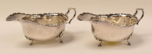 A PAIR OF SILVER SAUCE-BOATS with geometric decorative rims on three pad-feet and with c-scroll