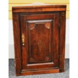 AN ANTIQUE HANGING CORNER CUPBOARD with brass fittings and inlaid centre cartouche to door and