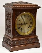 GERMAN, BLACK FOREST MANTEL CLOCK in a carved oak case with circular silvered dial bearing Roman