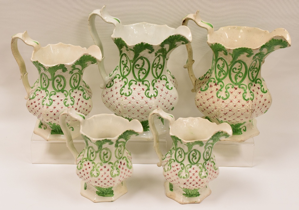 A SET OF FIVE NINETEENTH CENTURY STAFFORDSHIRE JUGS each of faceted form and with green and red