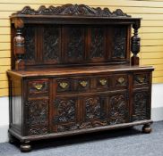 A LARGE CARVED OAK SIDEBOARD the base with four heavily carved cupboard doors and four carved